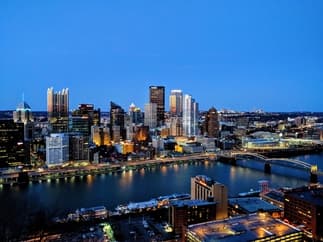 This is a birds eye view photo of the city of Pittsburgh after the sun has set.